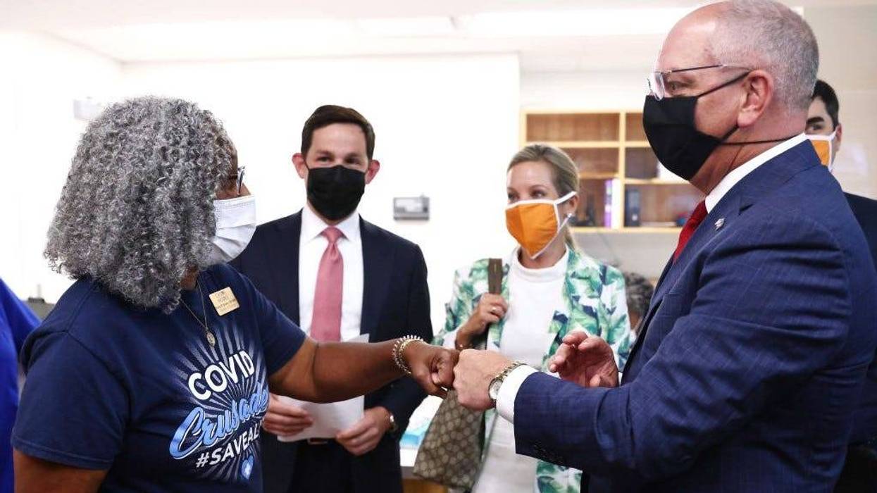 Nurse Carla Brown (L) fist bumps Louisiana Gov. John Bel Edwards at an event where the governor honored her for her vaccine work on August 17, 2021 in Baton Rouge, Louisiana.