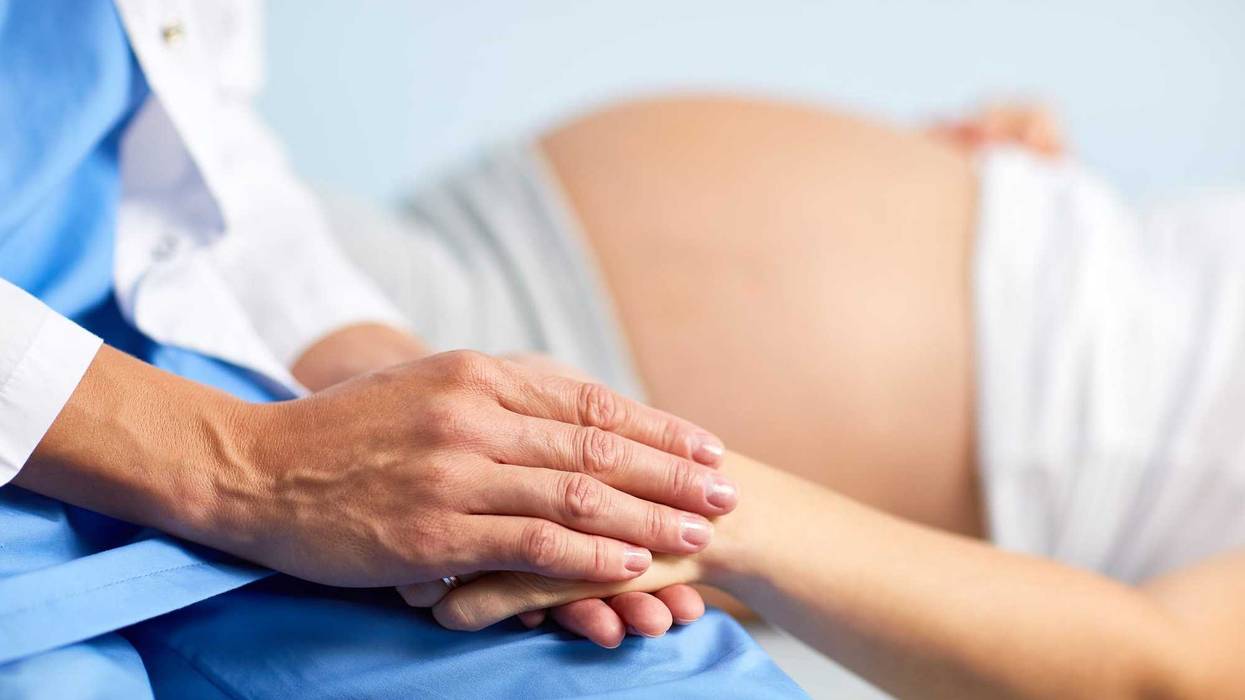 Nurse holding pregnant woman's hand.