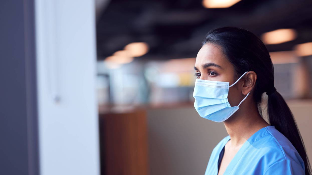 nurse wearing mask looks out window