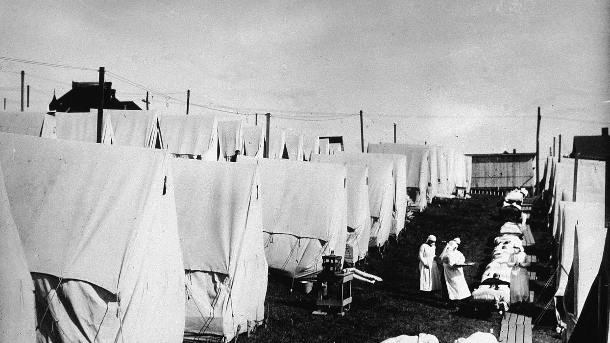 Nurses care for victims of the 1918 influenza pandemic outdoors amidst canvas tents in Lawrence, Massachusetts, 1918.