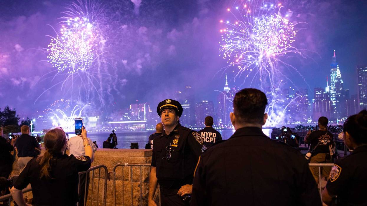 NYPD officers watch fireworks lighting up the night sky over the East River as seen from Hunter's Park South on July 4, 2021, in Queens