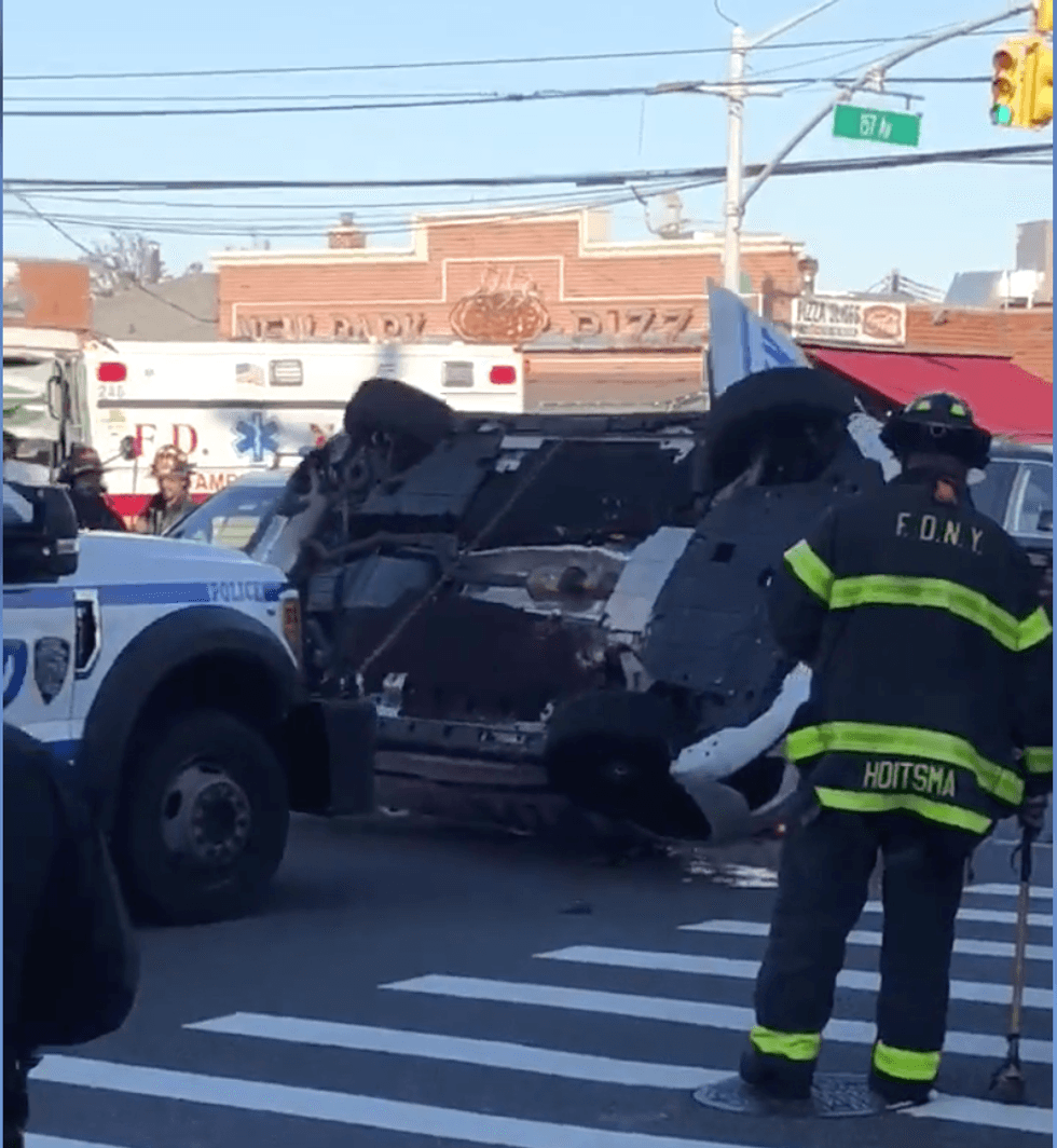 NYPD pulls the overturned cruiser back on its axis Saturday afternoon.