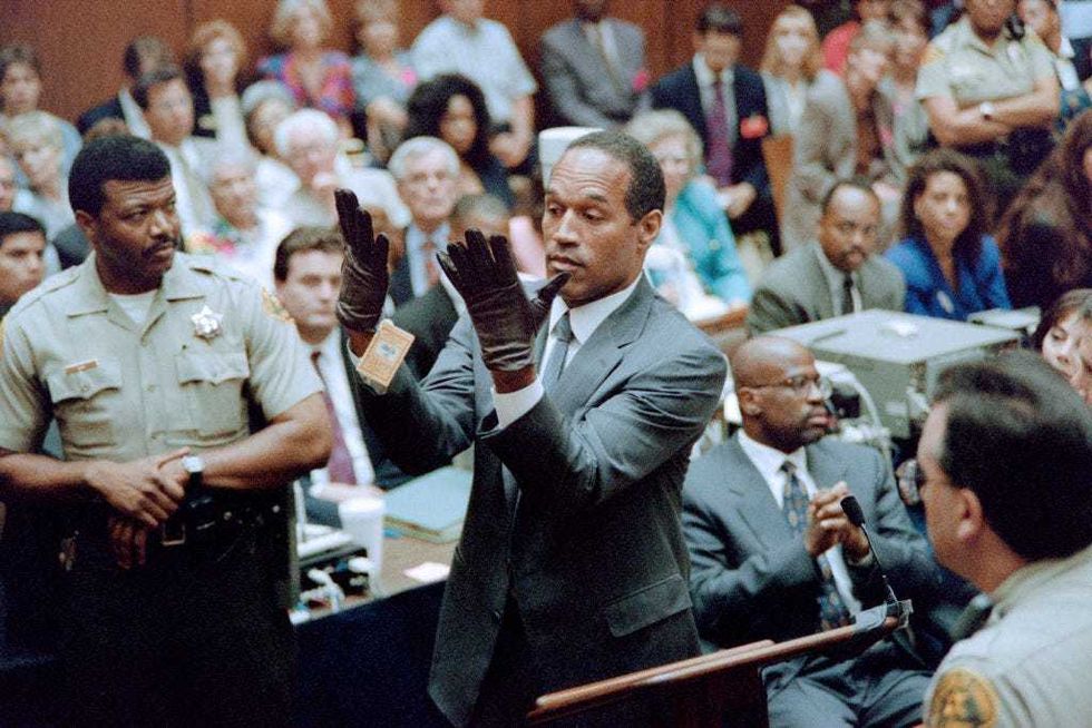 O.J. Simpson looks at a new pair of Aris extra-large gloves which the prosecutors had him put on for the jury 21 June 1995 during his double murder trial in Los Angeles. The gloves were the same type found at the Bundy murder scene and the O.J. Simpson estate.