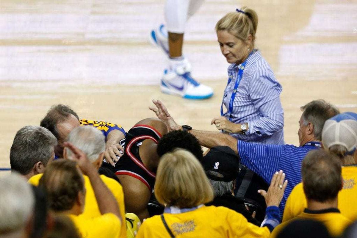 OAKLAND, CALIFORNIA - JUNE 05: Kyle Lowry #7 of the Toronto Raptors is pushed by Warriors minority investor Mark Stevens (blue shirt) after falling into the seats after a play against the Golden State Warriors in the second half during Game Three of the 2