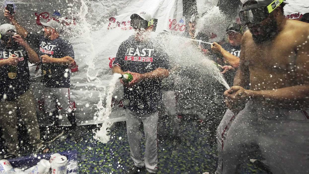 Oct 4, 2022; Miami, Florida, USA; Atlanta Braves manager Brian Snitker, center, and pitcher Kenley Jansen, right, celebrate winning the NL East division with a 2-1 victory over the Miami Marlins at loanDepot Park.