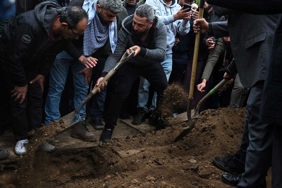 Oday Al-Fayoume (center in gray hoodie) places dirt over the casket of his 6-year-old son Wadea Al-Fayoume at Parkholm Cemetery on Monday, Oct. 16, 2023 in LaGrange, Ill.