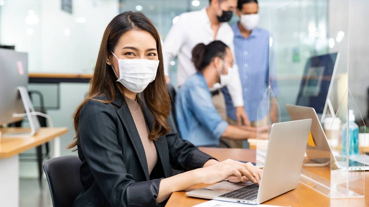 Office employee wearing a protective face mask at work to prevent the spread of COVID-19.