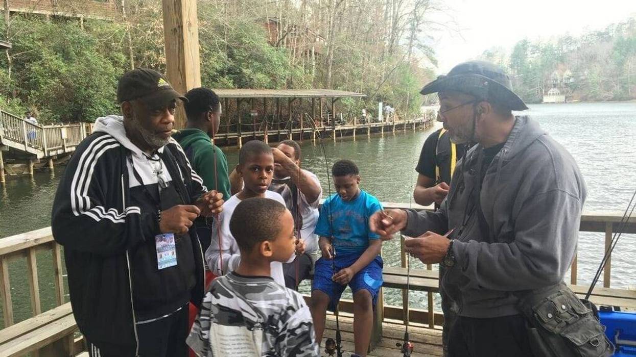 Officer Bruce Griggs (l) observes as the boys receive fishing lessons at YMCA Camp High HarboUr in Cartersville GA