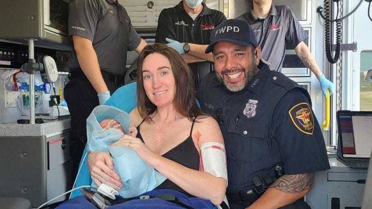 Officer Salazar and the woman he helped deliver her baby pose for a photo inside of an ambulance.