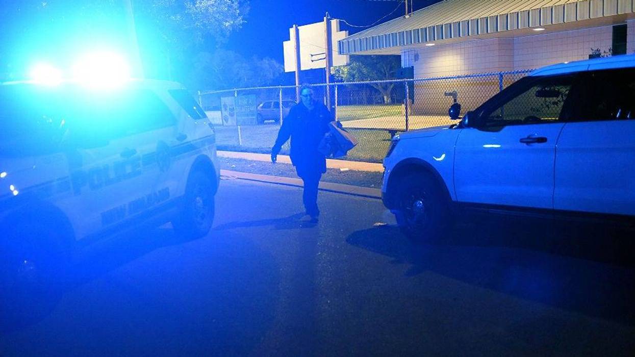 officer walks between two vehicles at a crime scene