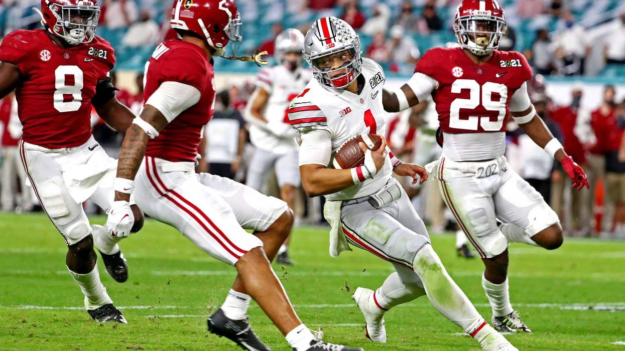 Ohio State Buckeyes quarterback Justin Fields (1) runs the ball against Alabama Crimson Tide linebacker Christian Harris (8) and defensive back DeMarcco Hellams (29) during the third quarter in the 2021 College Football Playoff National Championship Game.