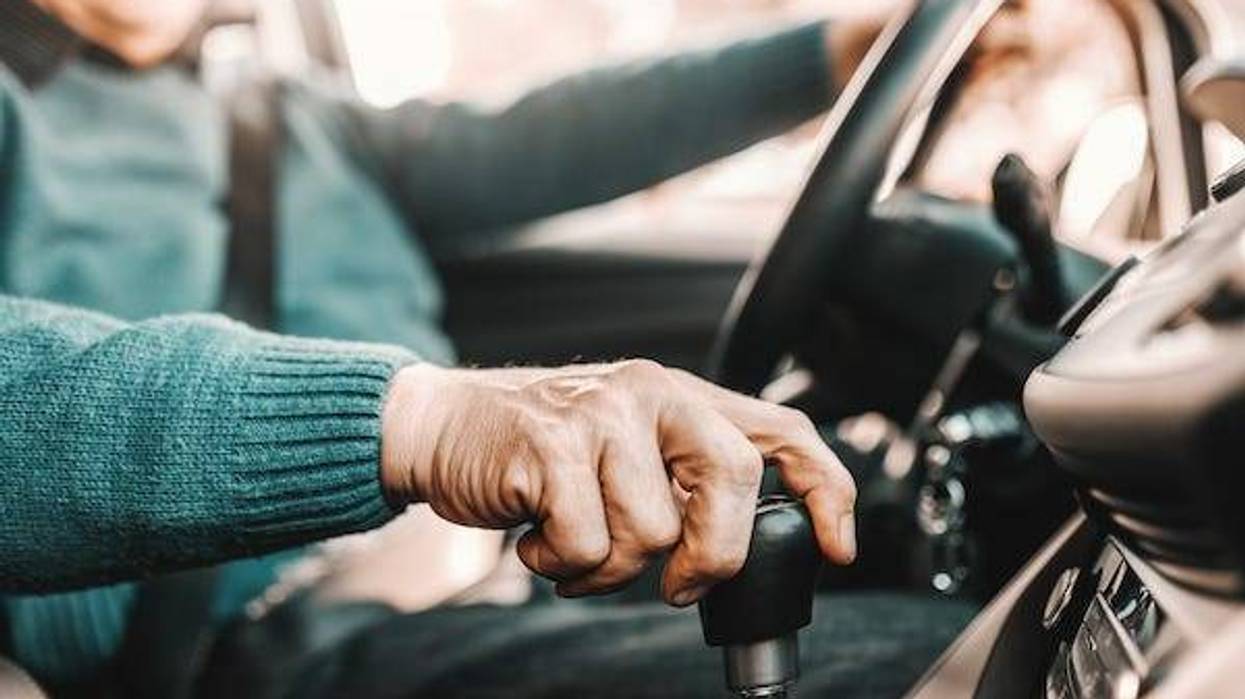 Old man driving with hand on stick shift
