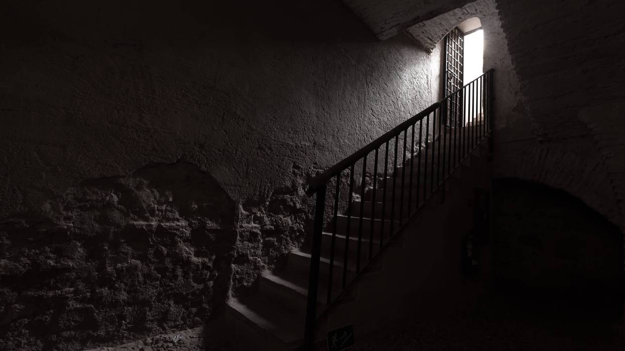 Old wrought iron stairs and light at the end of a tunnel