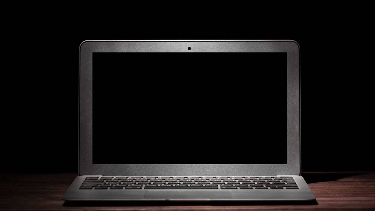 One silver modern laptop on wooden table in a dark room on black background. Nice mockup for your IT project. Dramatic light