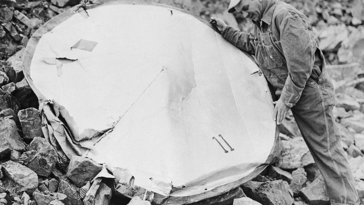 (Original Caption) 12/16/1952-West Orange, NJ: An object resembling a popular conception of "flying saucers" is inspected at a West Orange quarry by Ralph Young, employee of the Colonial Concrete Company, which operates at the quarry. The disk is constructed of heavy cardboard material and contains dangling circular wiring and a number of broken bulbs. A large "11" is painted on the surface. Authorities discounted theories that the disk was a hoax because of the innaccessibility to the clifon which it was found, and said its location and condition indicated it might have been dropped from an aircraft.