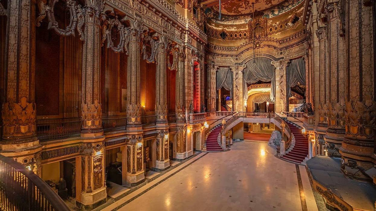 Ornate interior of Chicago’s Uptown Theatre, featuring marble floors, elaborate plasterwork, tall columns and a grand staircase beneath richly decorated ceilings.