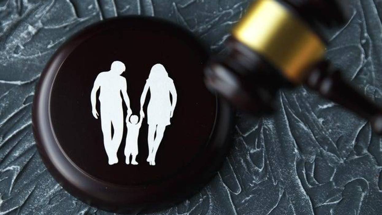 Outline of a man and woman holding hands with a child on a gavel