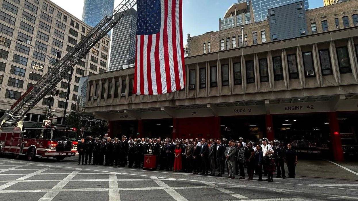 Outside Engine 42 in River North, city leaders and first responders stood shoulder to shoulder as two fire trucks stretched their ladders across Illinois Street, suspending a massive American flag.