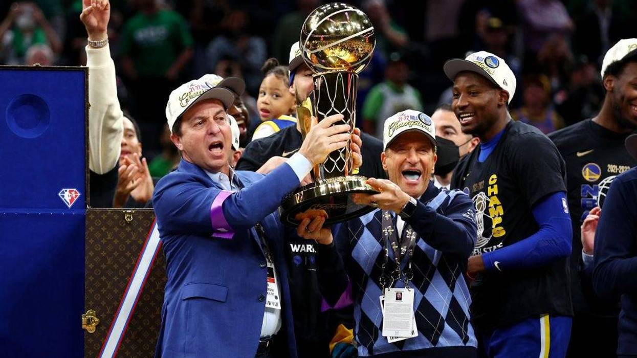 Owners Joe Lacob and Peter Guber of the Golden State Warriors raise the Larry O'Brien Championship Trophy after defeating the Boston Celtics 103-90 in Game Six of the 2022 NBA Finals at TD Garden on June 16, 2022 in Boston, Massachusetts