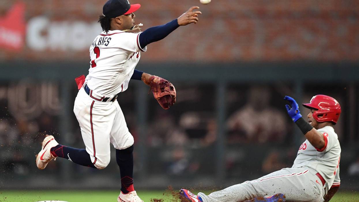 Ozzie Albies of the Atlanta Braves attempts to turn a double play against Jean Segura of the Philadelphia Phillies during the first inning at Truist Park on September 28, 2021 in Atlanta, Georgia.