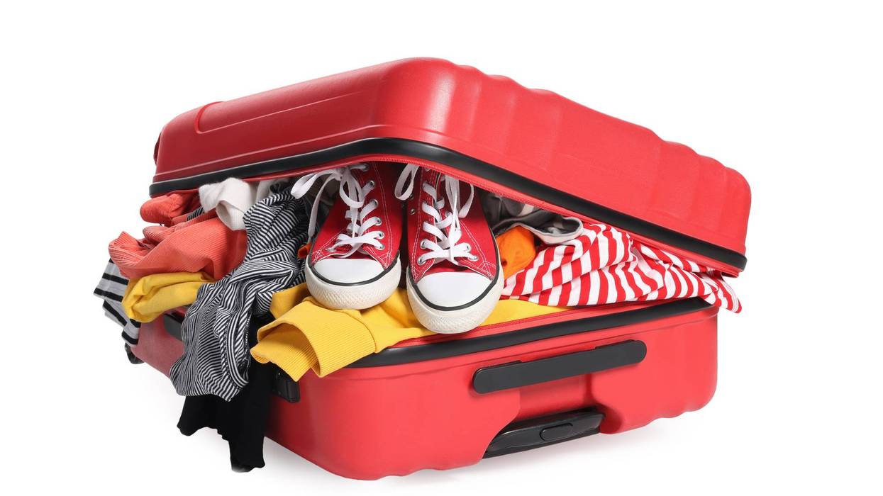 Packed suitcase full of clothes isolated on white