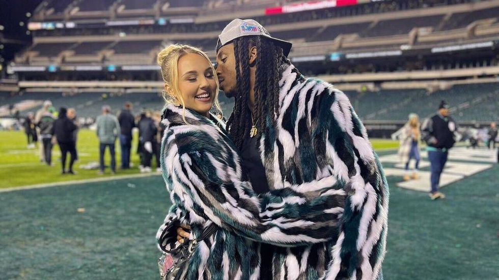 Paige Bieker and former Eagles safety Anthony Harris in faux fur coats at playoff after the Eagles advanced to Super Bowl LVII.