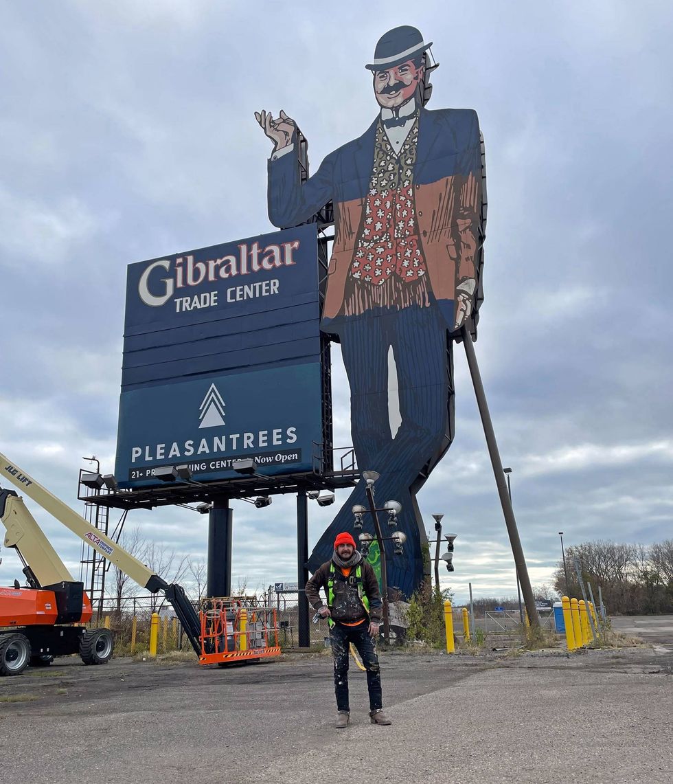 Painter Zak Warmann stands in front of the Gibraltar Trade Center sign in Mount Clemens, Mich., which he is retouching for Pleasantrees