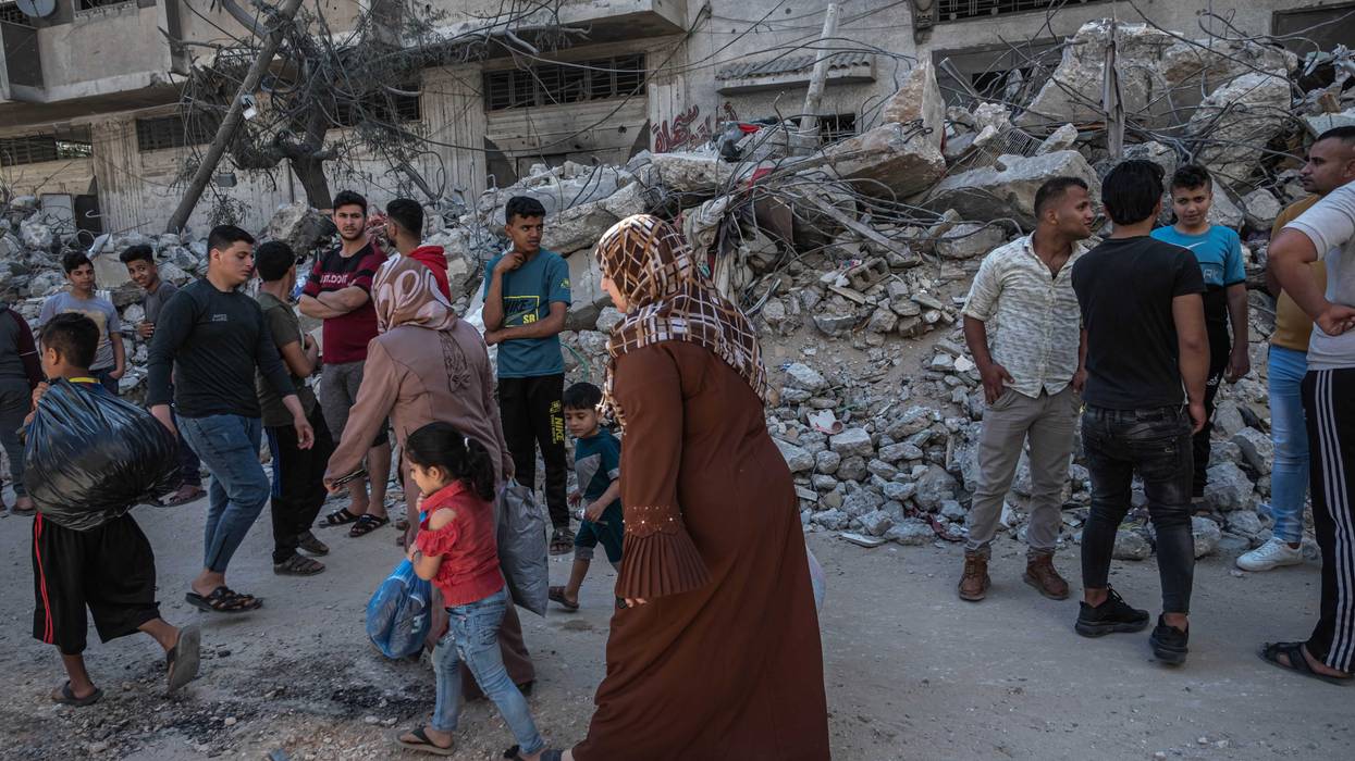 Palestinians walk past damaged buildings in al-Shati Refugee Camp west of Gaza City on May 15, 2021 in Gaza City, Gaza.