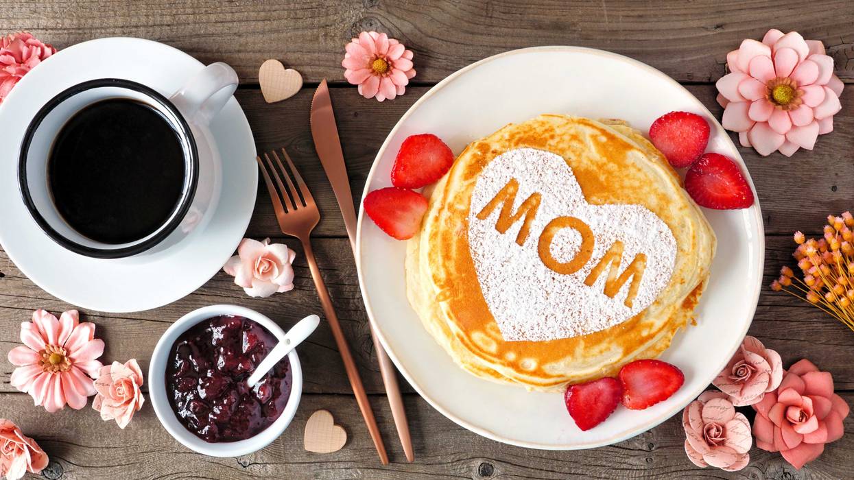 Pancakes with heart shape and MOM letters. Mothers Day breakfast concept. Overhead view table scene with a rustic wood background.
