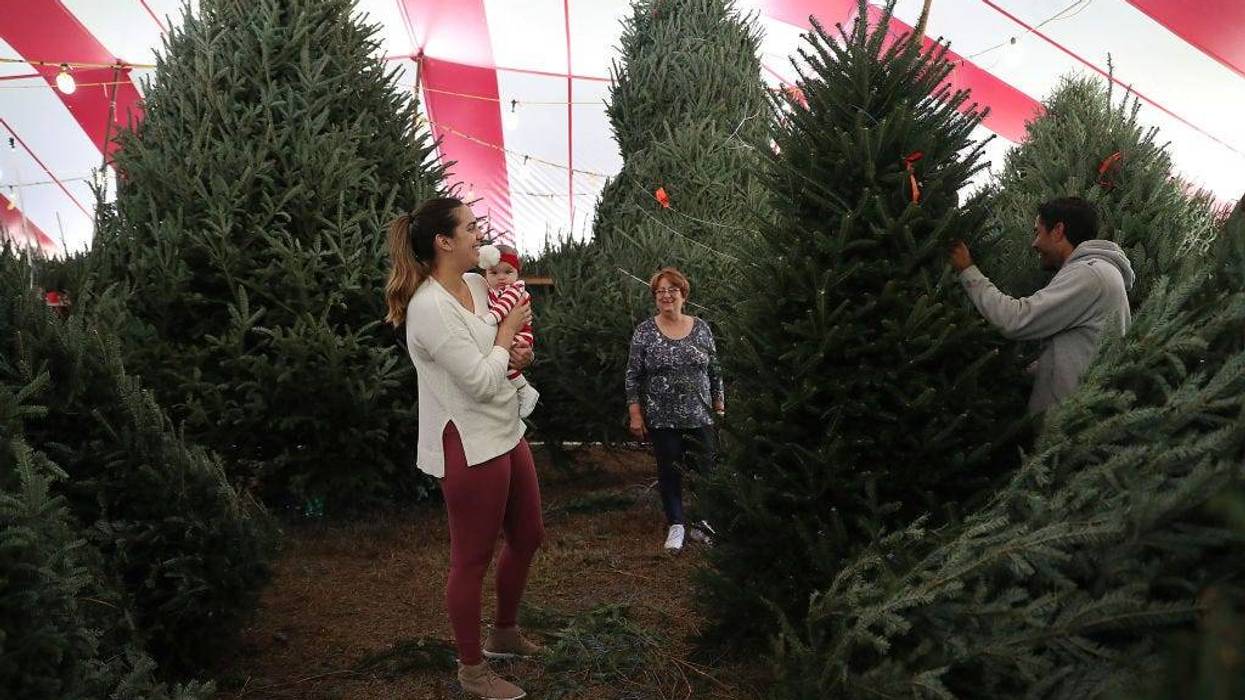 Paola Gonzalez holds her daughter Penelope Gonzalez, 3 months old, as she shops for a Christmas tree at a Holiday Sale Christmas Tree lot on November 29, 2018 in Miami, Florida.
