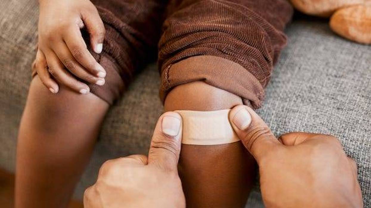 Parent putting a bandage on their child’s knee