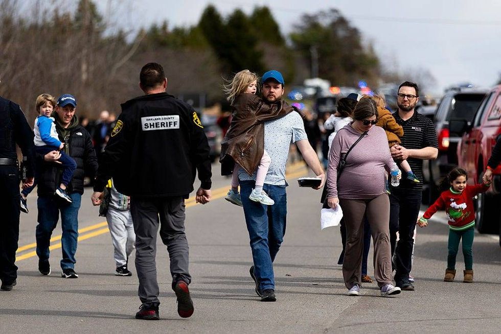 Parents carry their children to their cars as enforcement escorts families following an active shooter near Temple Israel on March 12, 2026 in West Bloomfield, Michigan.