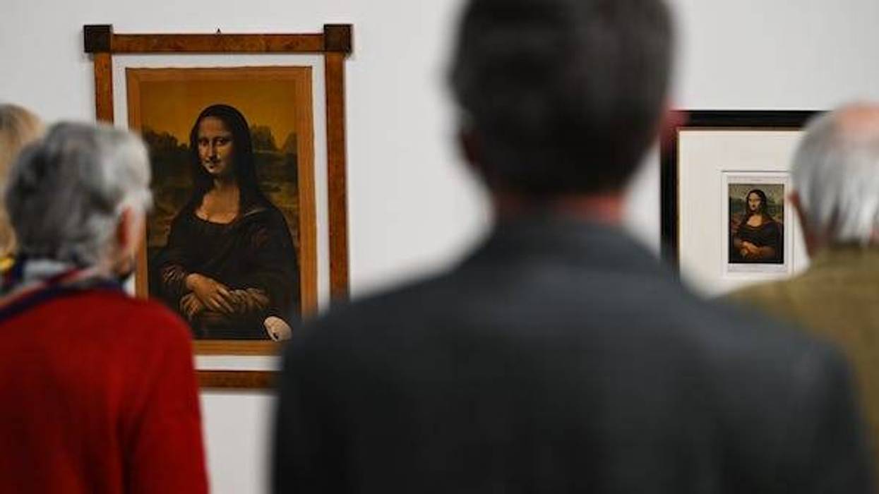 Participants in a press conference stand in front of reproductions of the Mona Lisa