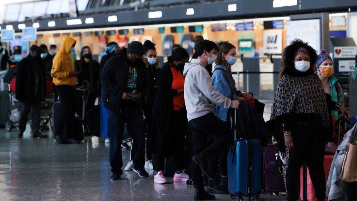 Passengers wait in line to check in for their flights at the Dulles International Airport on December 27, 2021 in Dulles, Virginia.