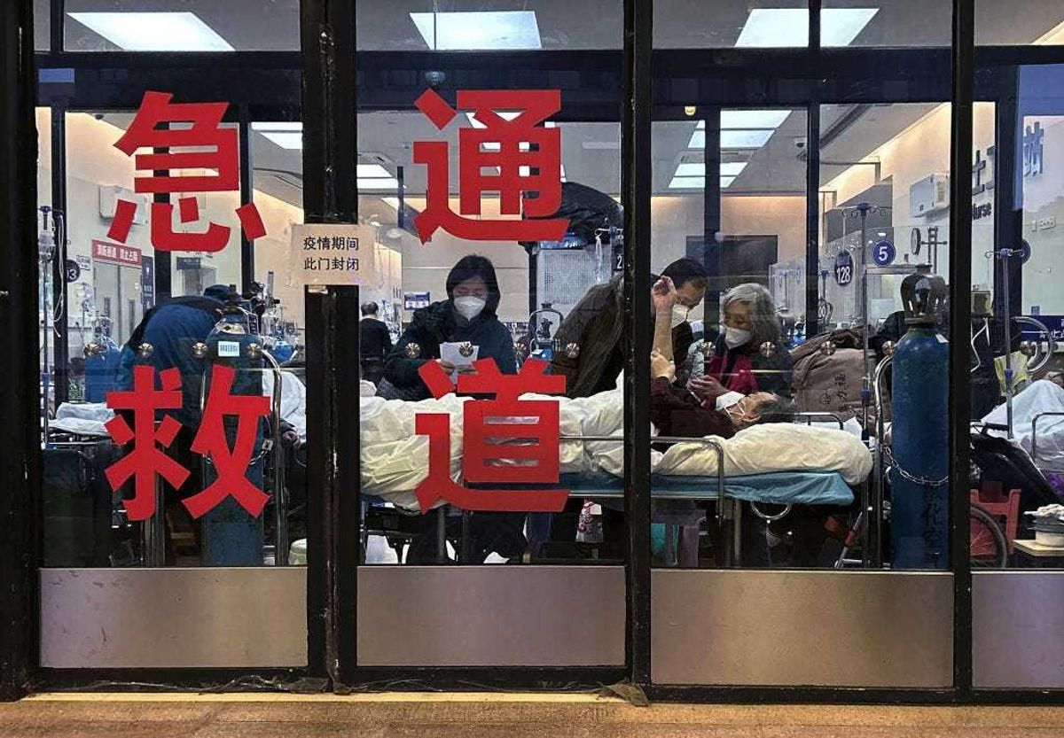 Patients and caregivers are seen in the closed entrance way of an emergency room being used as an overflow area at a hospital on January 14, 2023 in Shanghai, China.