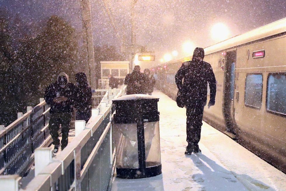 Patrons exit the Long Island Railroad (LIRR) train and are met with snow flurries on December 16, 2020 in Bethpage, New York.