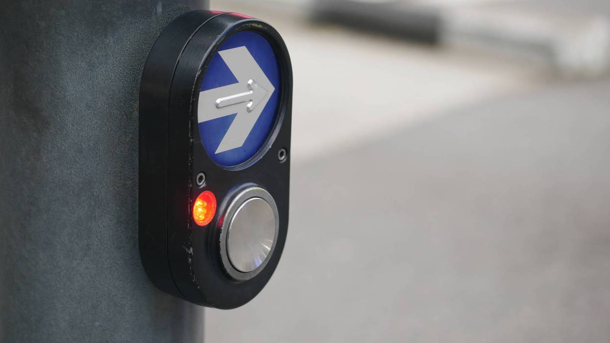 Pedestrian signal button at urban crosswalk during daytime