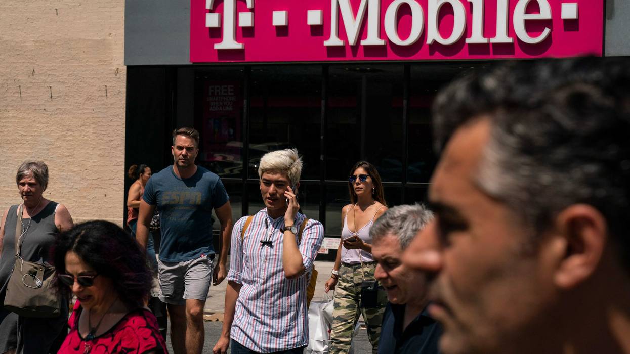 Pedestrians cross an intersection near a T-Mobile store on Sixth Avenue in Manhattan on July 26, 2019 in New York City.
