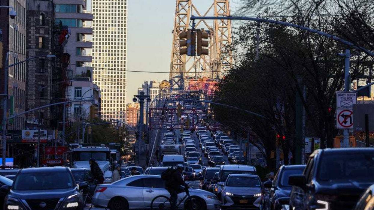 Pedestrians, cyclists and cars move along Delancey Street, with the Williamsburg Bridge in the background, in Manhattan on Nov. 13, 2024.