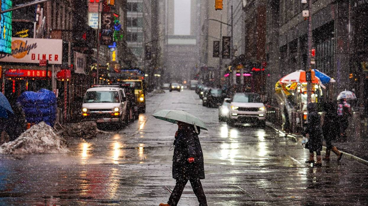 Pedestrians walk along the street as snow falls in New York on Feb. 22