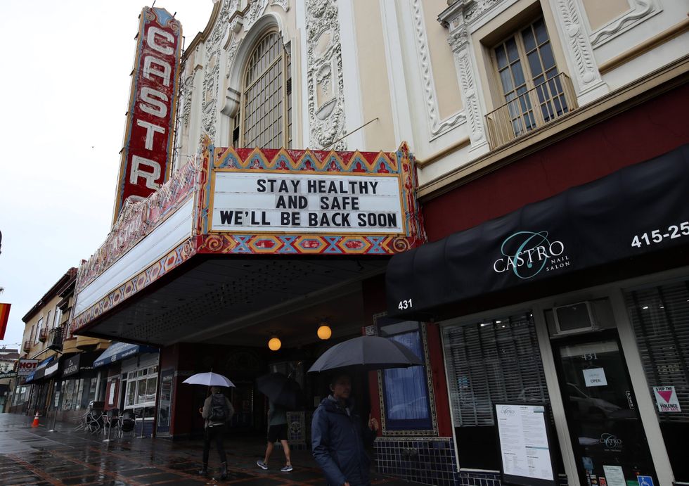 Pedestrians walk by the Castro Theatre that has a marquee announcing that they are closed due to a statewide ordinance banning gatherings of more than 250 people on March 15, 2020 in San Francisco, California.