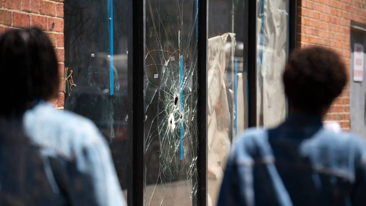 Pedestrians walk past bullet holes in the window of a storefront on South Street in Philadelphia, Pennsylvania, on June 5, 2022.