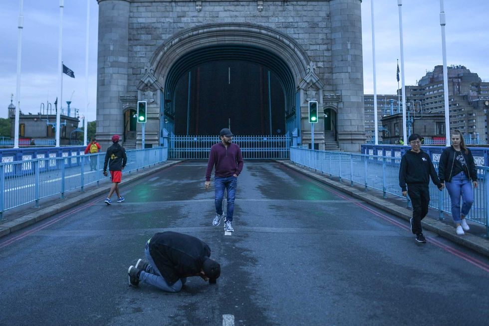People are seen taking photos on Tower Bridge, which is stuck in the raised position.