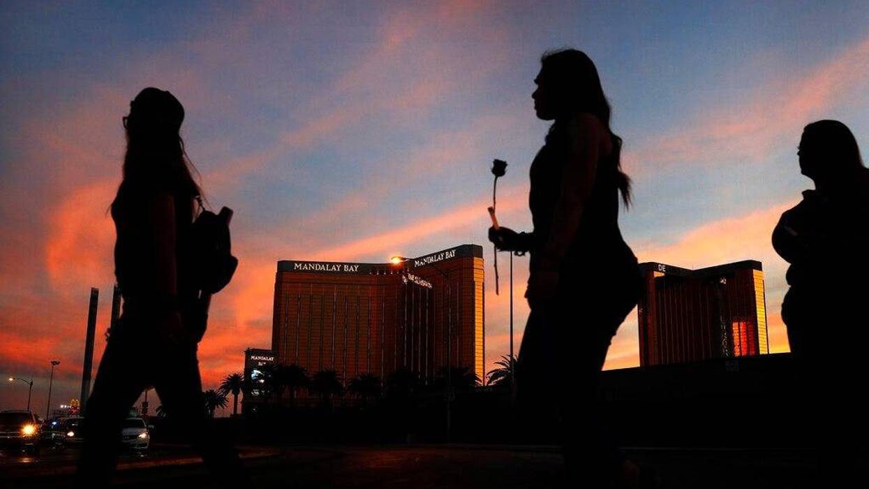 people carry flowers as they walk near the Mandalay Bay hotel and casino during a vigil for victims and survivors of a mass shooting in Las Vegas.
