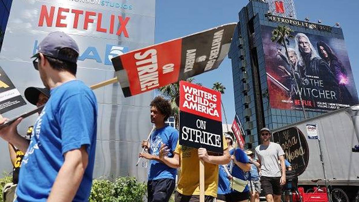 People carry signs as SAG-AFTRA members walk the picket line in solidarity with striking WGA (Writers Guild of America) workers outside Netflix offices on July 11, 2023 in Los Angeles, California.