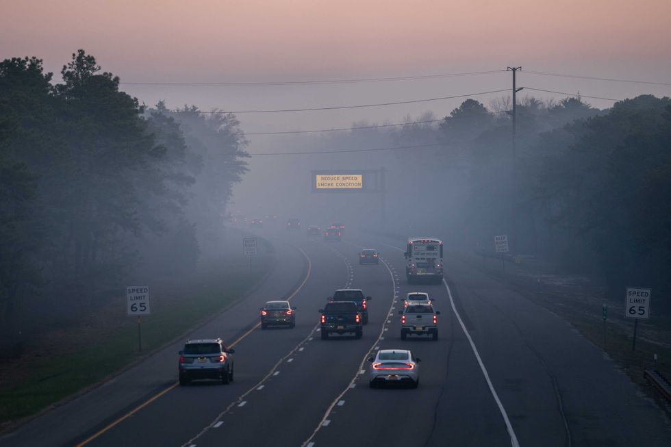 People drive on the Garden State Parkway as a matrix sign warns of smoke conditions on April 24, 2025