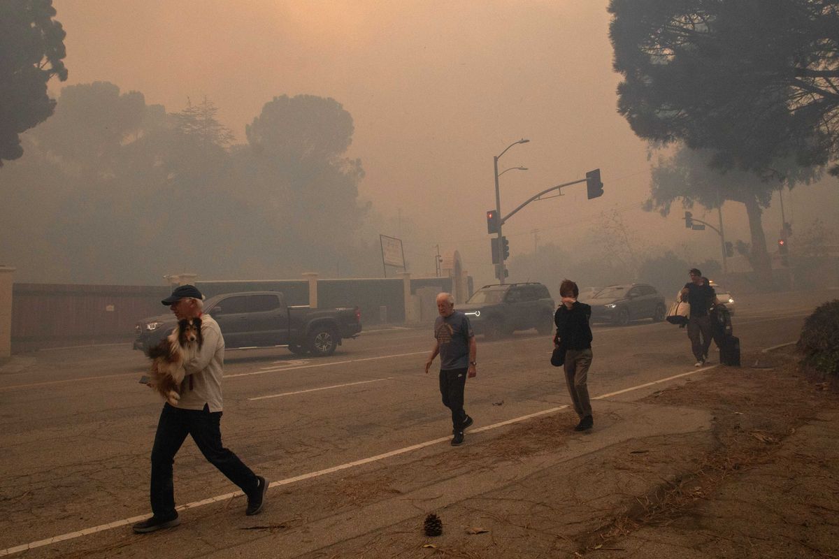 People evacuate along Sunset Boulevard as the Palisades Fire burns amid a powerful windstorm on January 7, 2025 in the Pacific Palisades neighborhood of Los Angeles, California. The fast-moving wildfire is threatening homes in the coastal neighborhood amid intense Santa Ana Winds and dry conditions in Southern California.