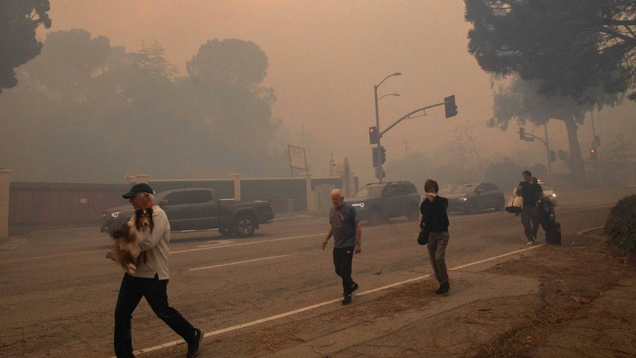 People evacuate along Sunset Boulevard as the Palisades Fire burns amid a powerful windstorm on January 7, 2025 in the Pacific Palisades neighborhood of Los Angeles, California. The fast-moving wildfire is threatening homes in the coastal neighborhood amid intense Santa Ana Winds and dry conditions in Southern California.