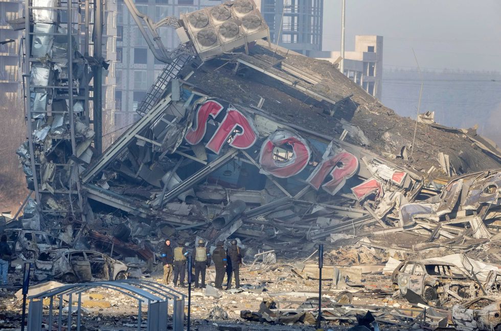 People examine the damage after shelling of a shopping center, in Kyiv, Ukraine, Monday, March 21, 2022. Eight people were killed in the attack
