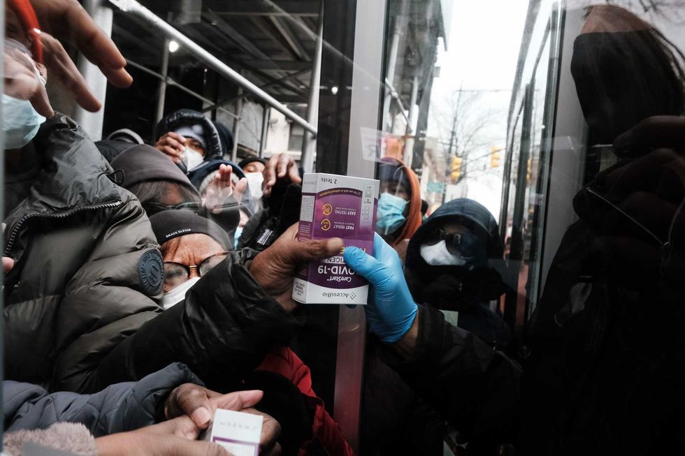 People form a large crowd as they attempt to receive COVID-19 testing kits from city workers distributing the kits along Flatbush Avenue in Brooklyn on Dec. 24, 2021